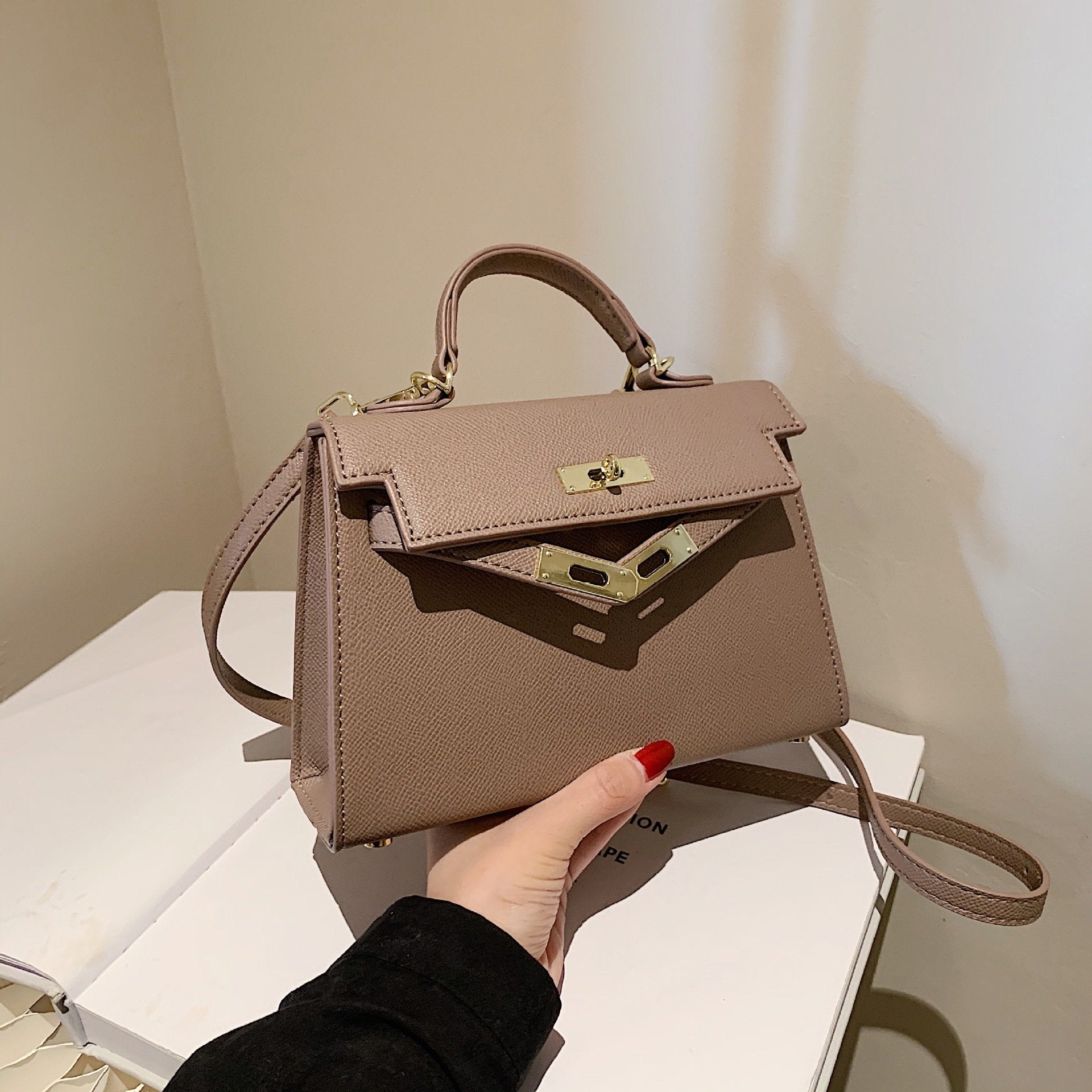 A woman carrying a small square bag with a lock