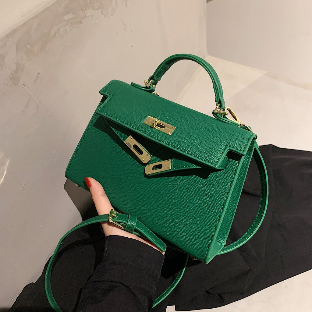 A woman carrying a small square bag with a lock