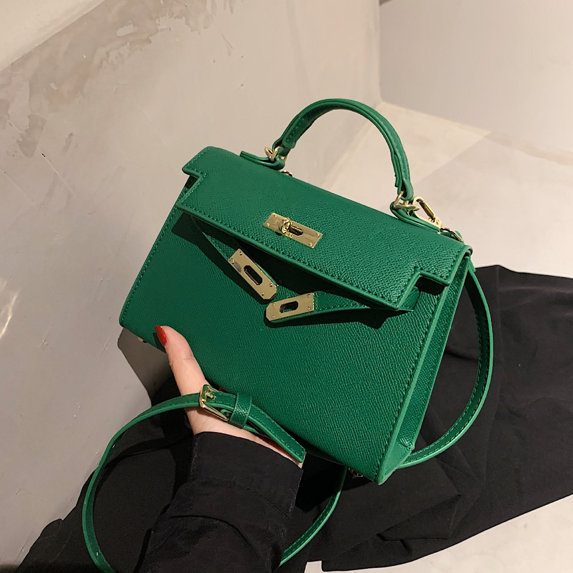 A woman carrying a small square bag with a lock